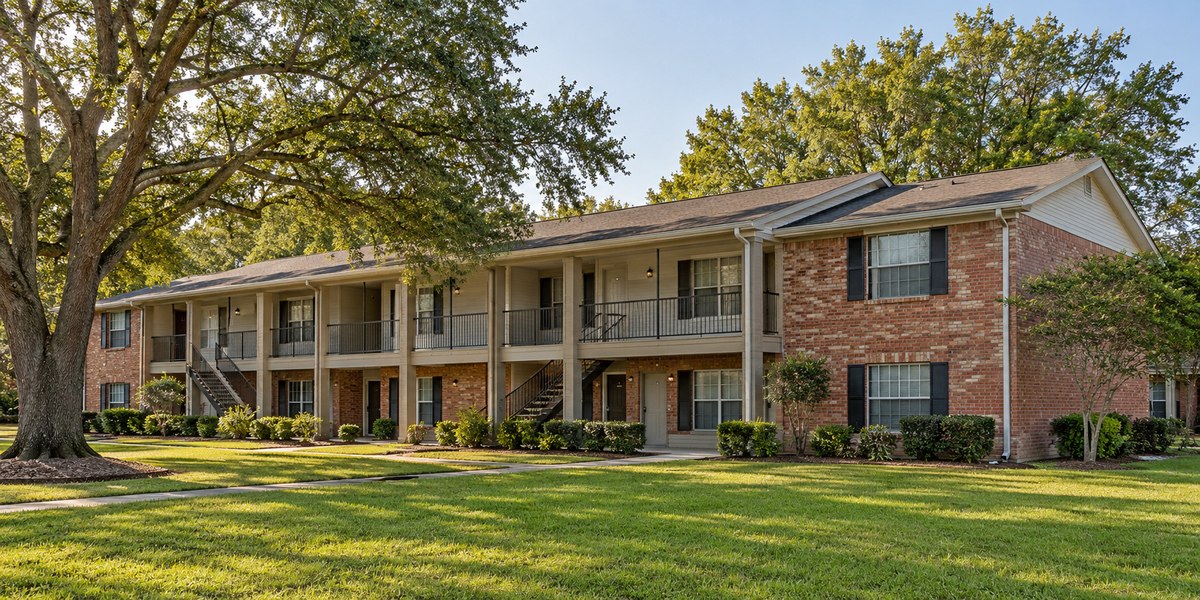 A small brick and siding apartment building with a landscaped walkway